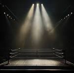 A boxing ring illuminated by spotlights in a dimly lit arena.