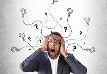 A man in a suit is holding his head in frustration, surrounded by swirling question marks.
