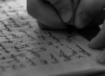 Close-up of a hand writing on a piece of paper filled with text.