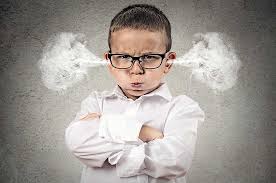 A young boy with glasses fuming in anger, arms crossed, with steam coming out of his ears, against a textured gray background.
